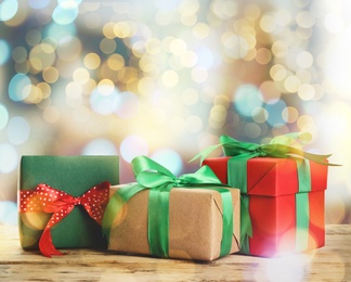 Christmas gift boxes on wooden table against blurred background, bokeh effect Image of Christmas gift boxes on wooden table against blurred background, bokeh effect