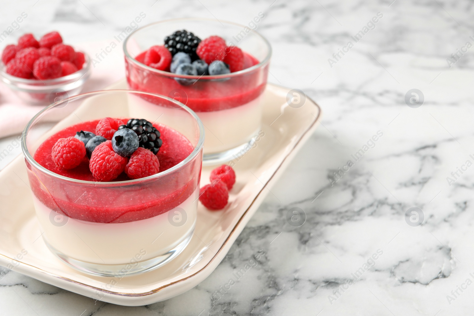 Delicious panna cotta with fruit coulis and fresh berries served on white marble table. Space for text Photo of Delicious panna cotta with fruit coulis and fresh berries served on white marble table. Space for text