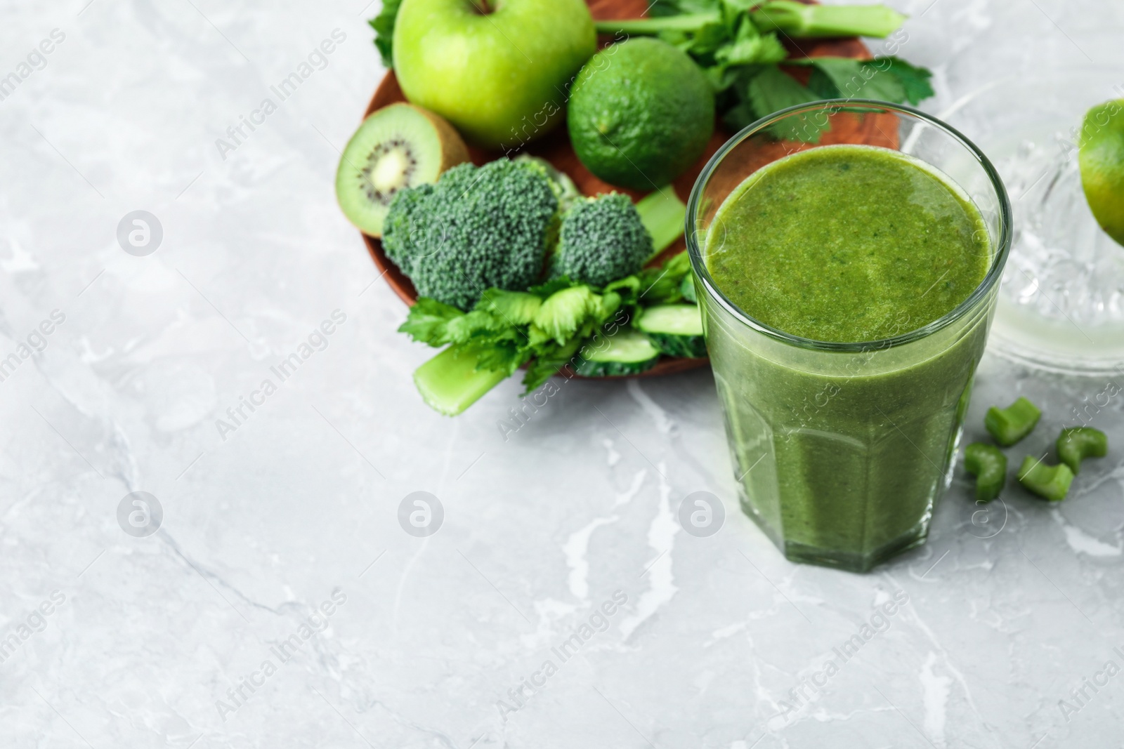 Photo of Delicious green juice and fresh ingredients on grey marble table, space for text