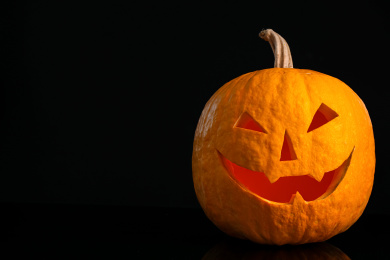 Pumpkin with scary face on black background. Halloween traditional decor Photo of Pumpkin with scary face on black background. Halloween traditional decor
