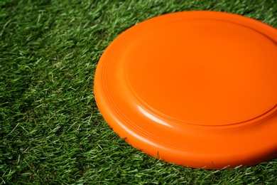 Orange plastic frisbee disk on green grass, closeup Photo of Orange plastic frisbee disk on green grass, closeup