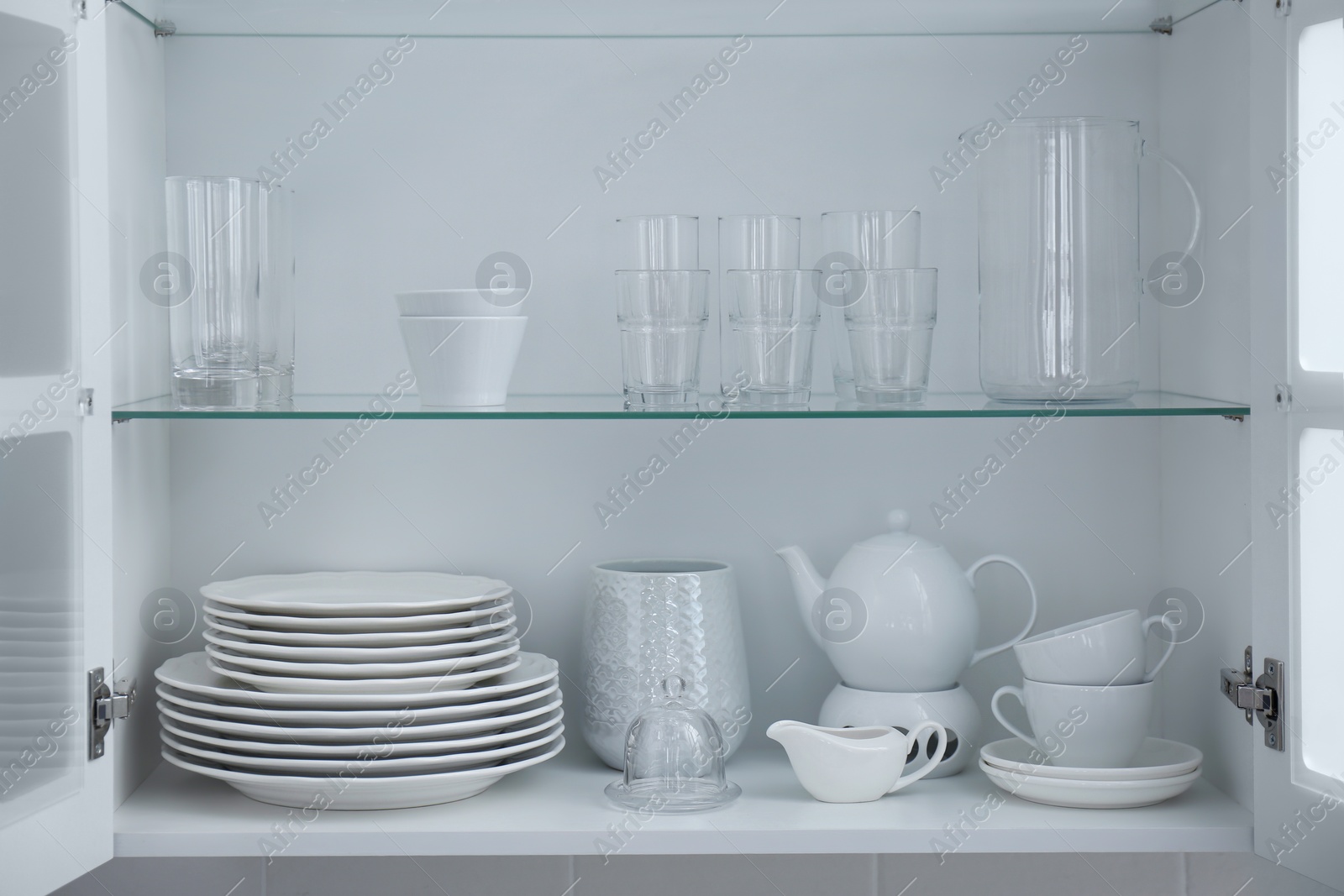 Cabinet with crockery and glassware. Order in kitchen Photo of Cabinet with crockery and glassware. Order in kitchen