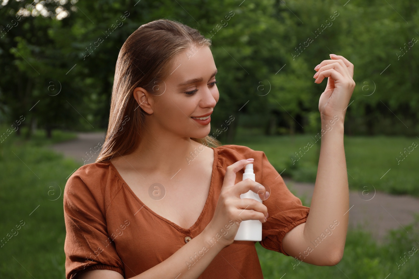Woman applying insect repellent onto arm in park. Tick bites prevention Photo of Woman applying insect repellent onto arm in park. Tick bites prevention