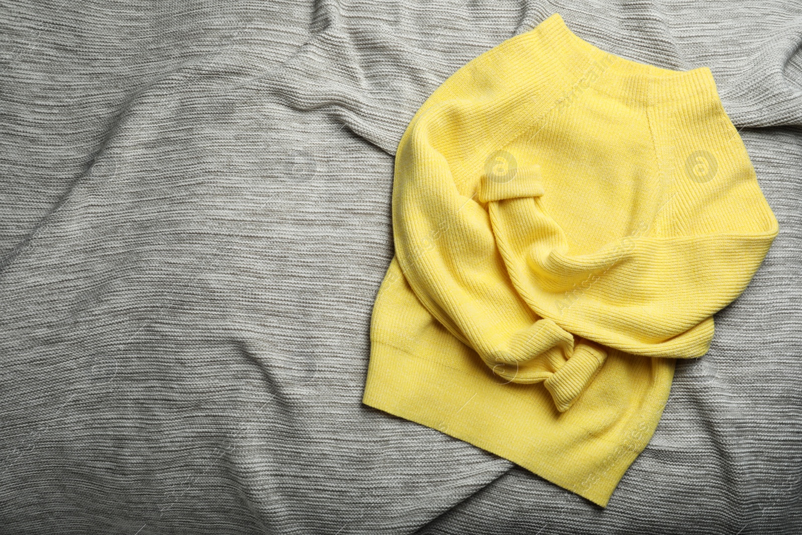 Yellow warm sweater on grey plaid, top view. Space for text Photo of Yellow warm sweater on grey plaid, top view. Space for text