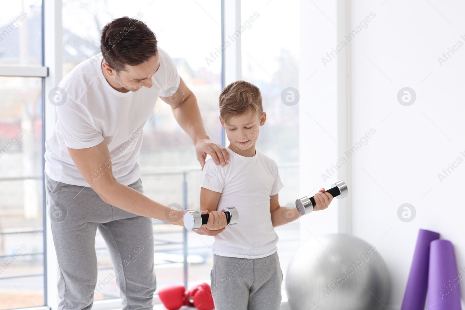Dad and his son training with dumbbells in gym Photo of Dad and his son training with dumbbells in gym