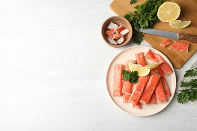 Flat lay composition with crab sticks, knife and lemon on white table, space for text Photo of Flat lay composition with crab sticks, knife and lemon on white table, space for text