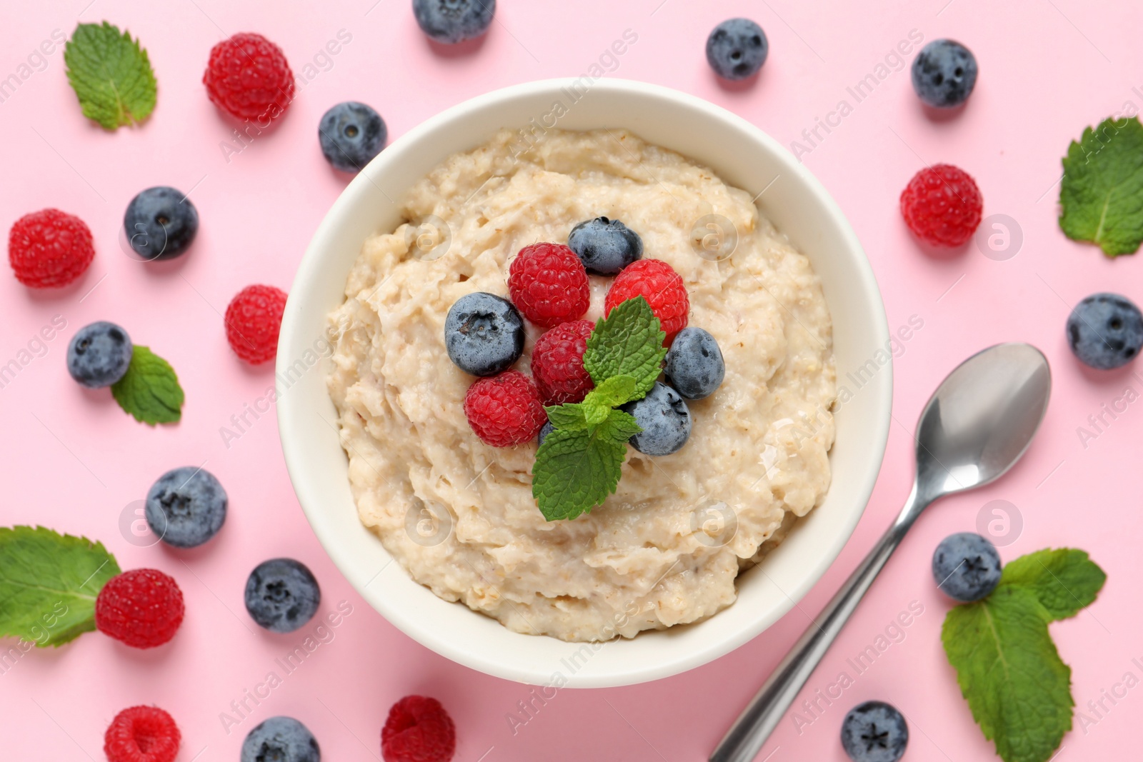 Tasty oatmeal porridge with raspberries and blueberries in bowl on pink background, flat lay Photo of Tasty oatmeal porridge with raspberries and blueberries in bowl on pink background, flat lay