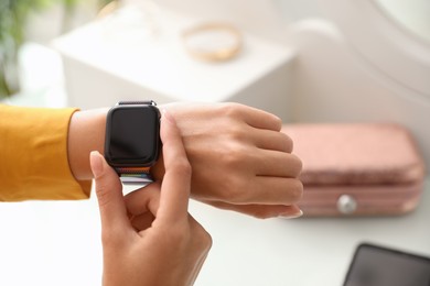 Woman checking stylish smart watch at home, closeup Image of Woman checking stylish smart watch at home, closeup