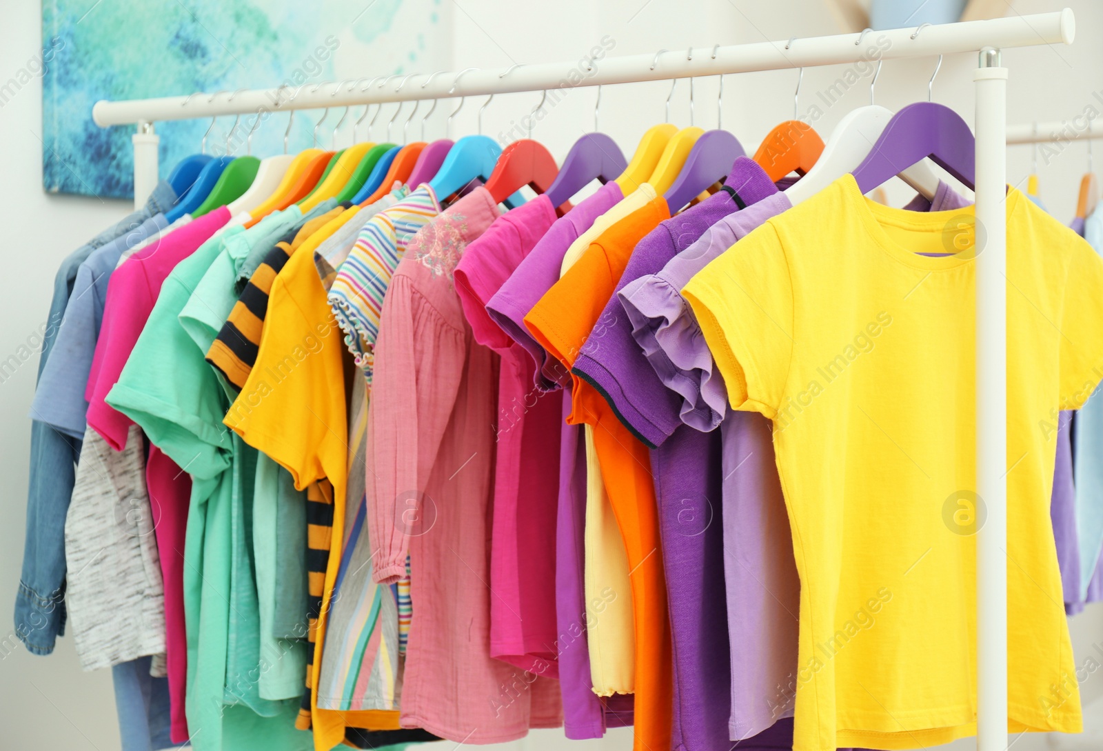 Different child's clothes hanging on rack in room Photo of Different child's clothes hanging on rack in room
