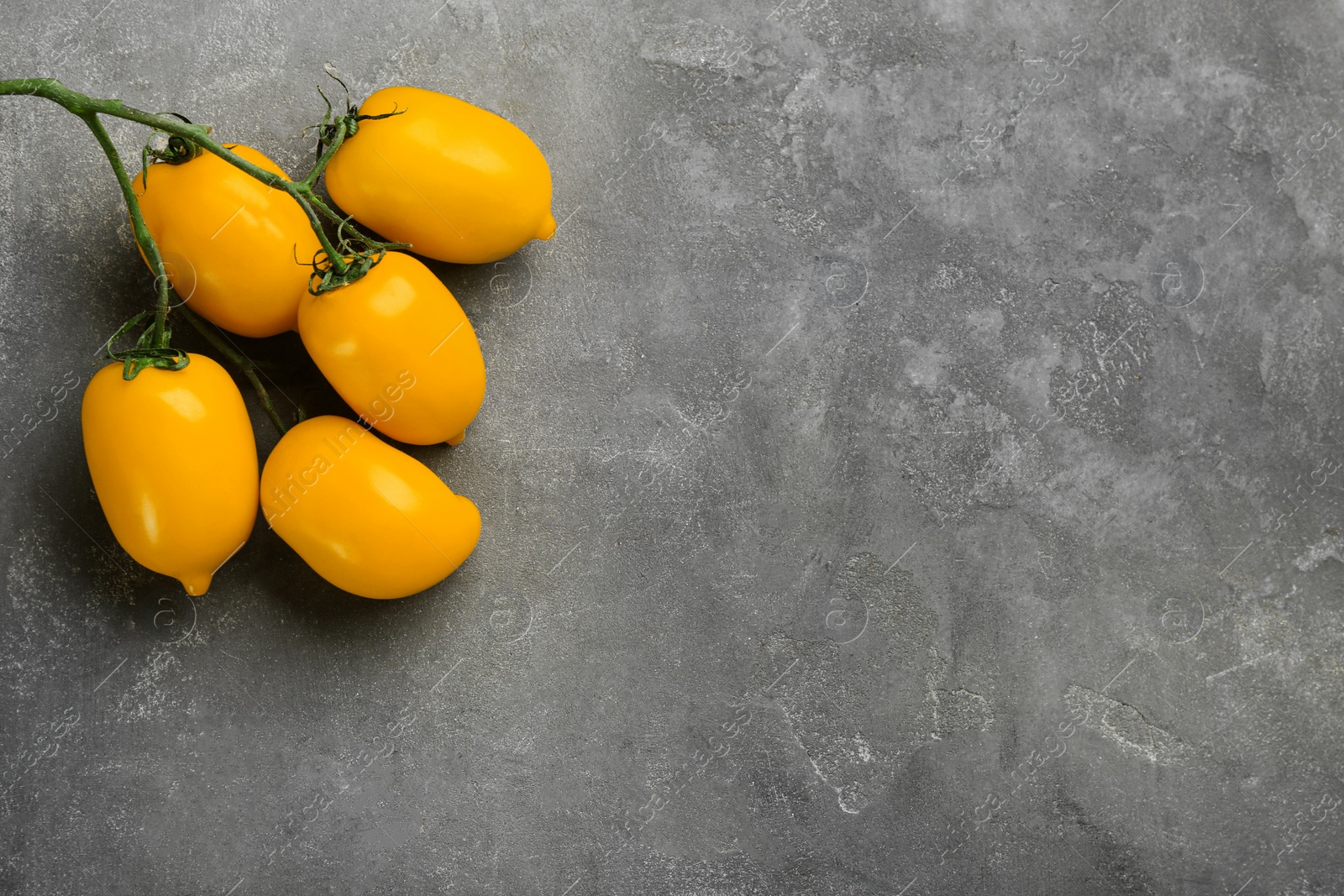 Ripe yellow tomatoes on grey table, flat lay. Space for text Photo of Ripe yellow tomatoes on grey table, flat lay. Space for text