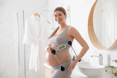 Young pregnant woman with scales in bathroom Photo of Young pregnant woman with scales in bathroom
