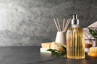 Stylish dispenser with liquid soap and other bathroom amenities on dark table, space for text Photo of Stylish dispenser with liquid soap and other bathroom amenities on dark table, space for text