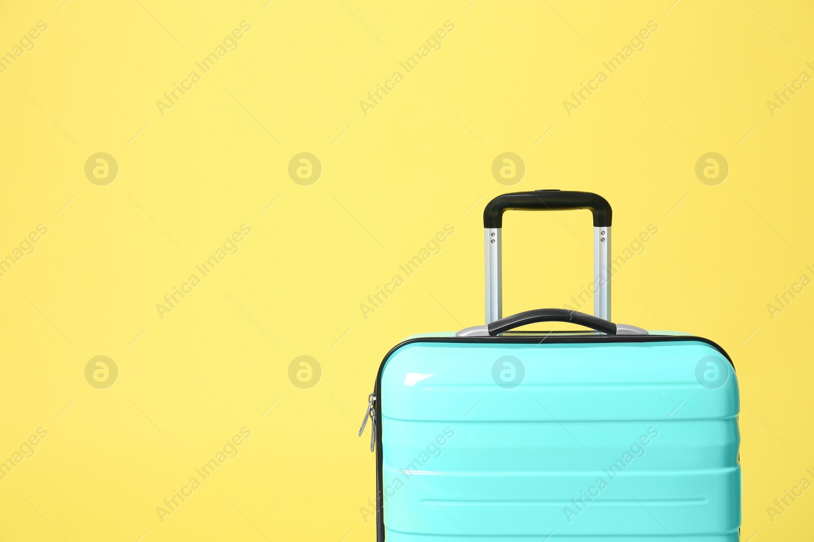 Photo of Stylish turquoise suitcase on yellow background. Space for text