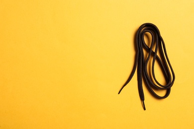Photo of Brown shoelace on yellow background, top view. Space for text