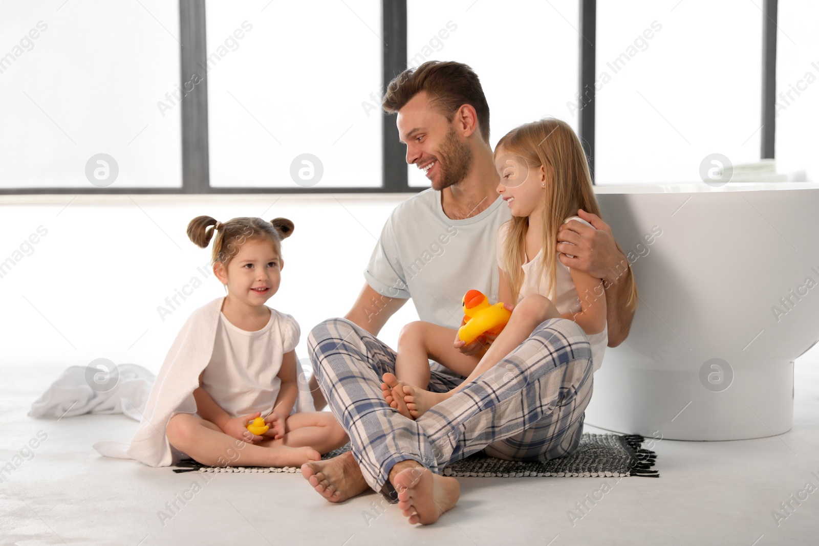 Father with little daughters near tub in bathroom Photo of Father with little daughters near tub in bathroom