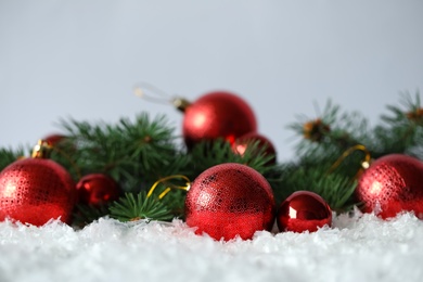 Beautiful Christmas balls and fir branches on snow against grey background. Space for text Photo of Beautiful Christmas balls and fir branches on snow against grey background. Space for text