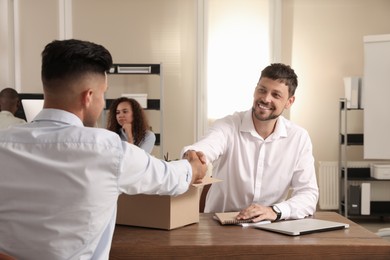 Employee shaking hand with new coworker in office Photo of Employee shaking hand with new coworker in office