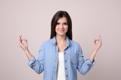 Young woman meditating on light background. Stress relief exercise Photo of Young woman meditating on light background. Stress relief exercise