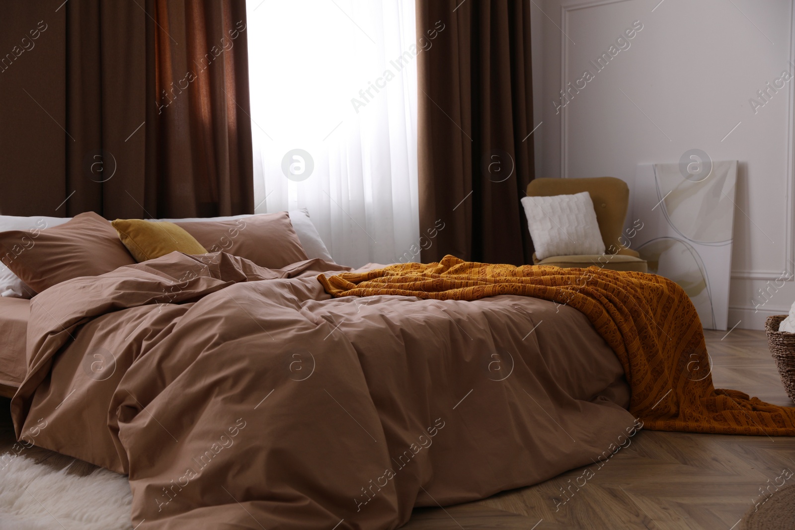 Bed with brown linens in stylish room interior Photo of Bed with brown linens in stylish room interior