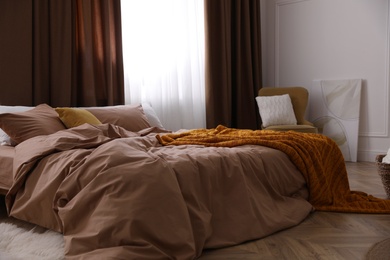Bed with brown linens in stylish room interior Photo of Bed with brown linens in stylish room interior