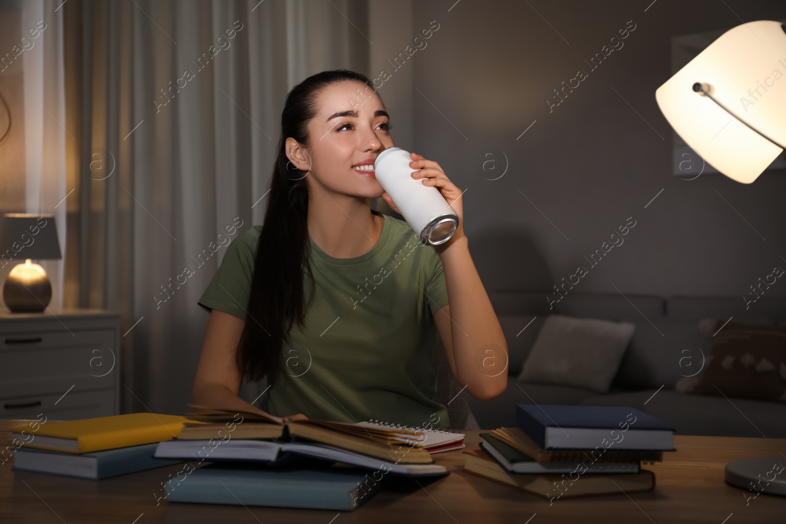 Young woman with energy drink studying at home Photo of Young woman with energy drink studying at home