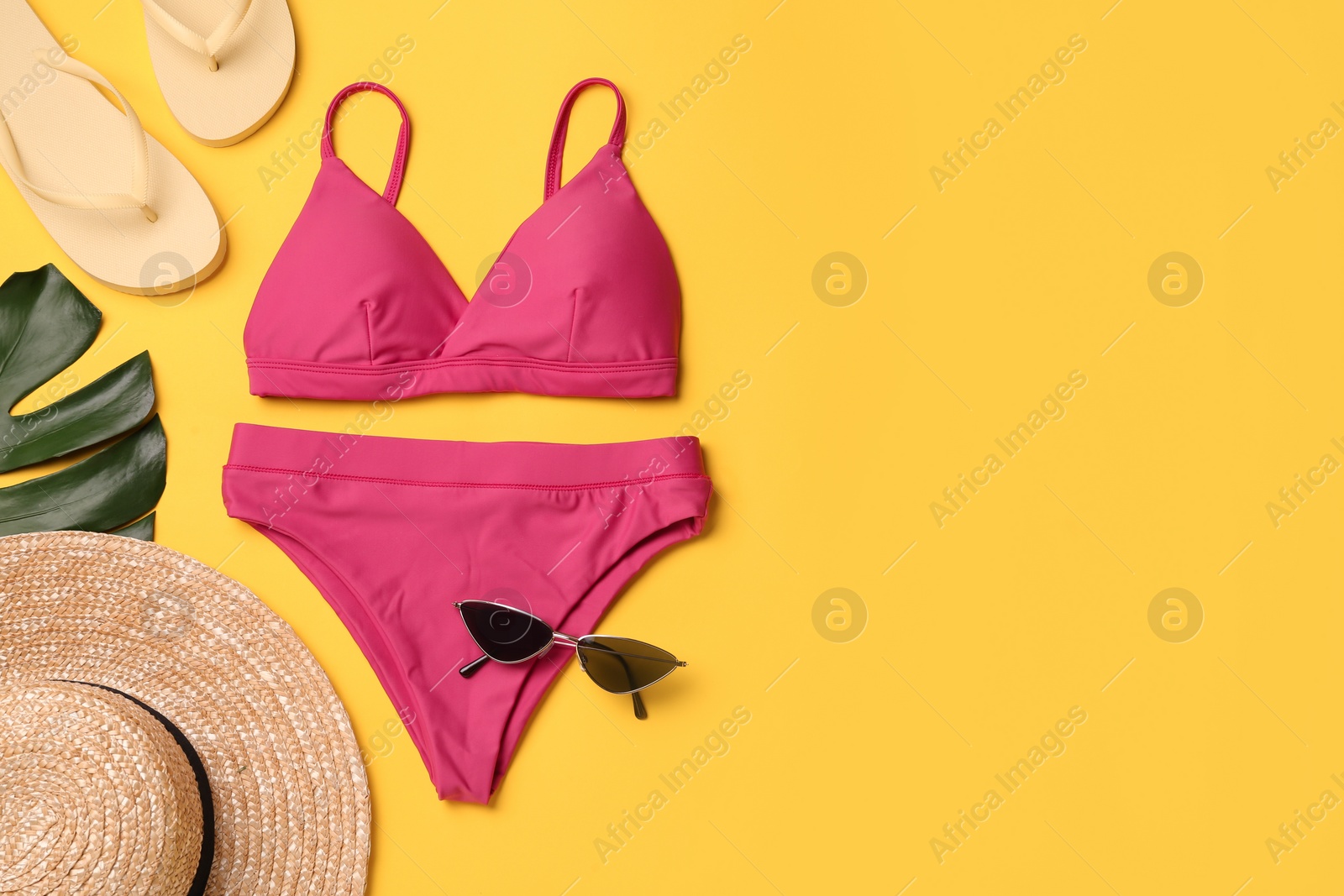 Stylish bikini and beach accessories on yellow background, flat lay. Space for text Photo of Stylish bikini and beach accessories on yellow background, flat lay. Space for text
