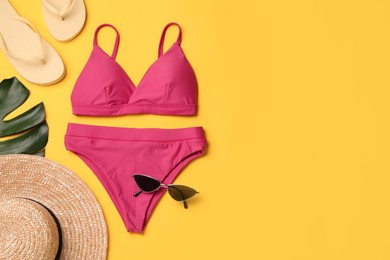 Photo of Stylish bikini and beach accessories on yellow background, flat lay. Space for text