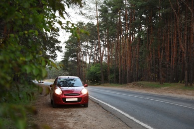Red car parked near forest. Road trip Photo of Red car parked near forest. Road trip