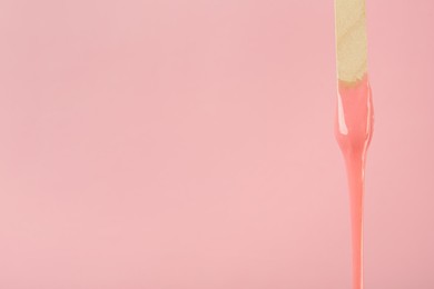 Wooden spatula with hot depilatory wax on pink background. Space for text Photo of Wooden spatula with hot depilatory wax on pink background. Space for text