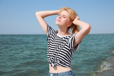 Beautiful young woman near sea on sunny day in summer Photo of Beautiful young woman near sea on sunny day in summer