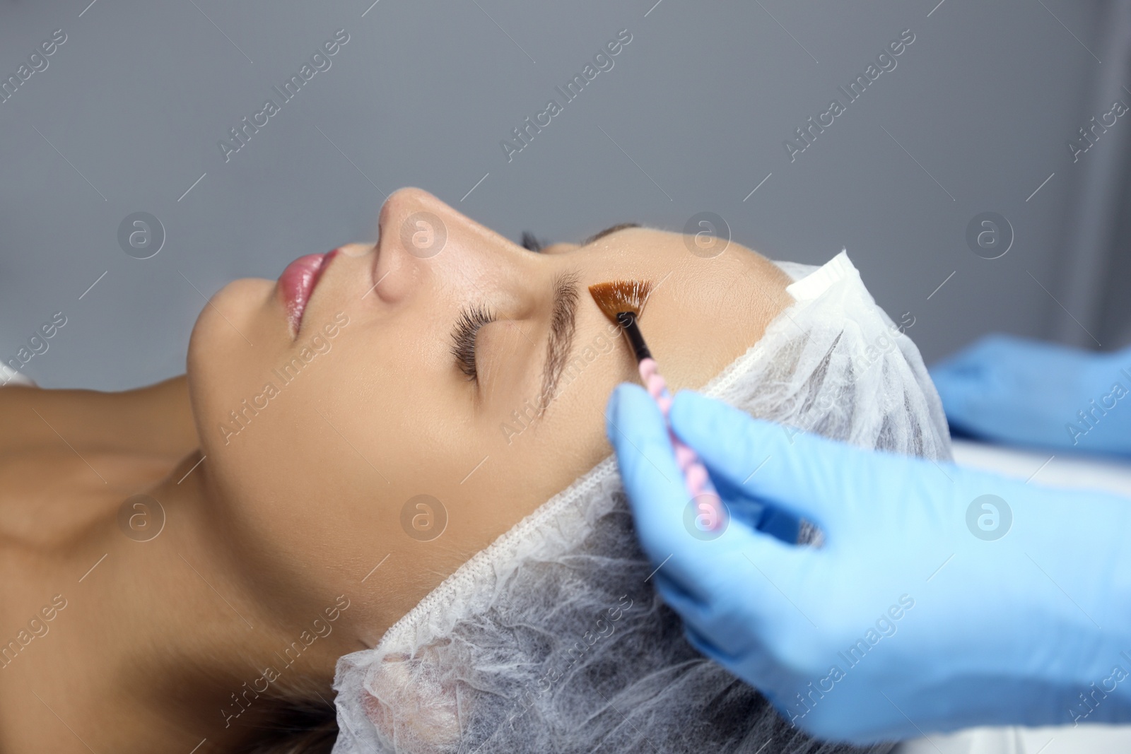 Cosmetologist applying chemical peel product on client's face in salon Photo of Cosmetologist applying chemical peel product on client's face in salon