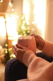 Woman holding cup of hot drink with marshmallows indoors, closeup. Magic Christmas atmosphere Photo of Woman holding cup of hot drink with marshmallows indoors, closeup. Magic Christmas atmosphere