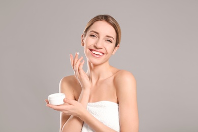 Young woman with jar of body cream on color background Photo of Young woman with jar of body cream on color background