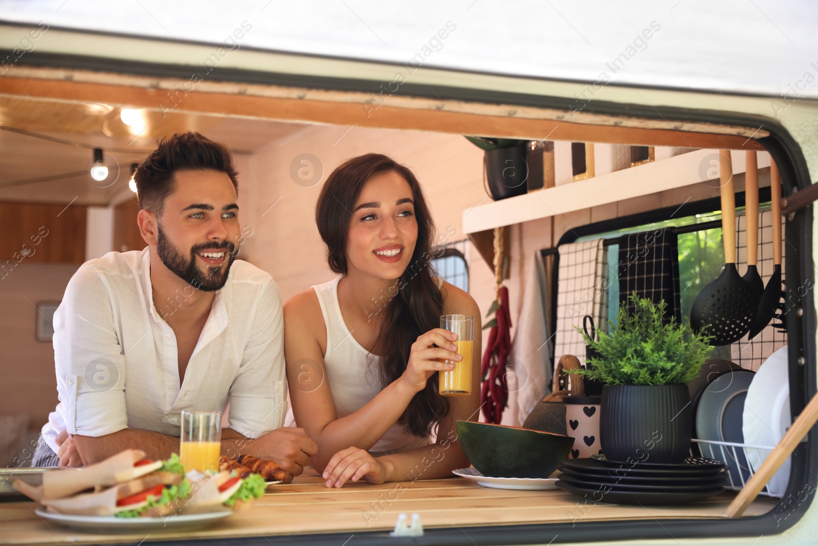 Happy young couple having breakfast in trailer. Camping vacation Photo of Happy young couple having breakfast in trailer. Camping vacation