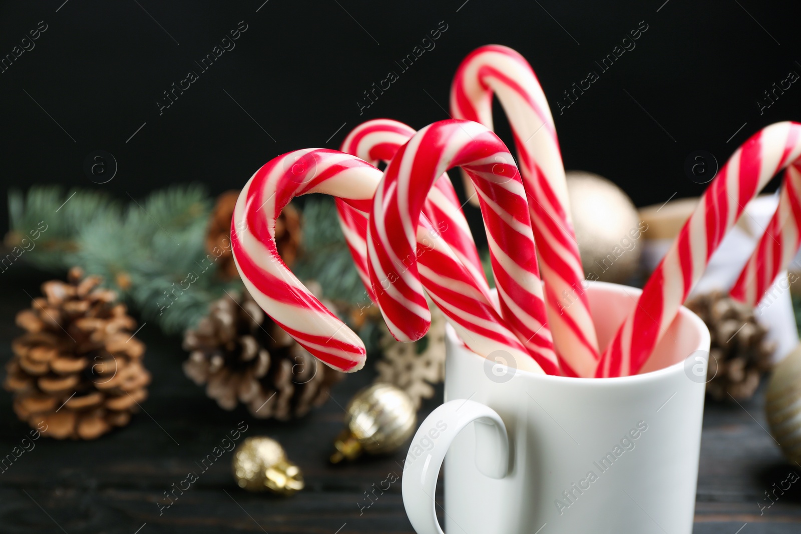 Many sweet candy canes and Christmas decor on black wooden table Photo of Many sweet candy canes and Christmas decor on black wooden table