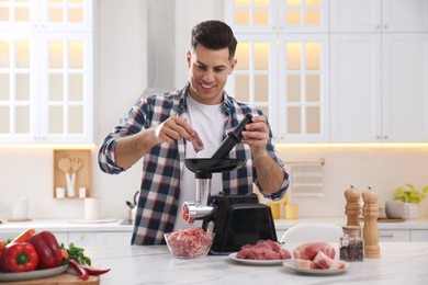 Man using modern meat grinder in kitchen Photo of Man using modern meat grinder in kitchen