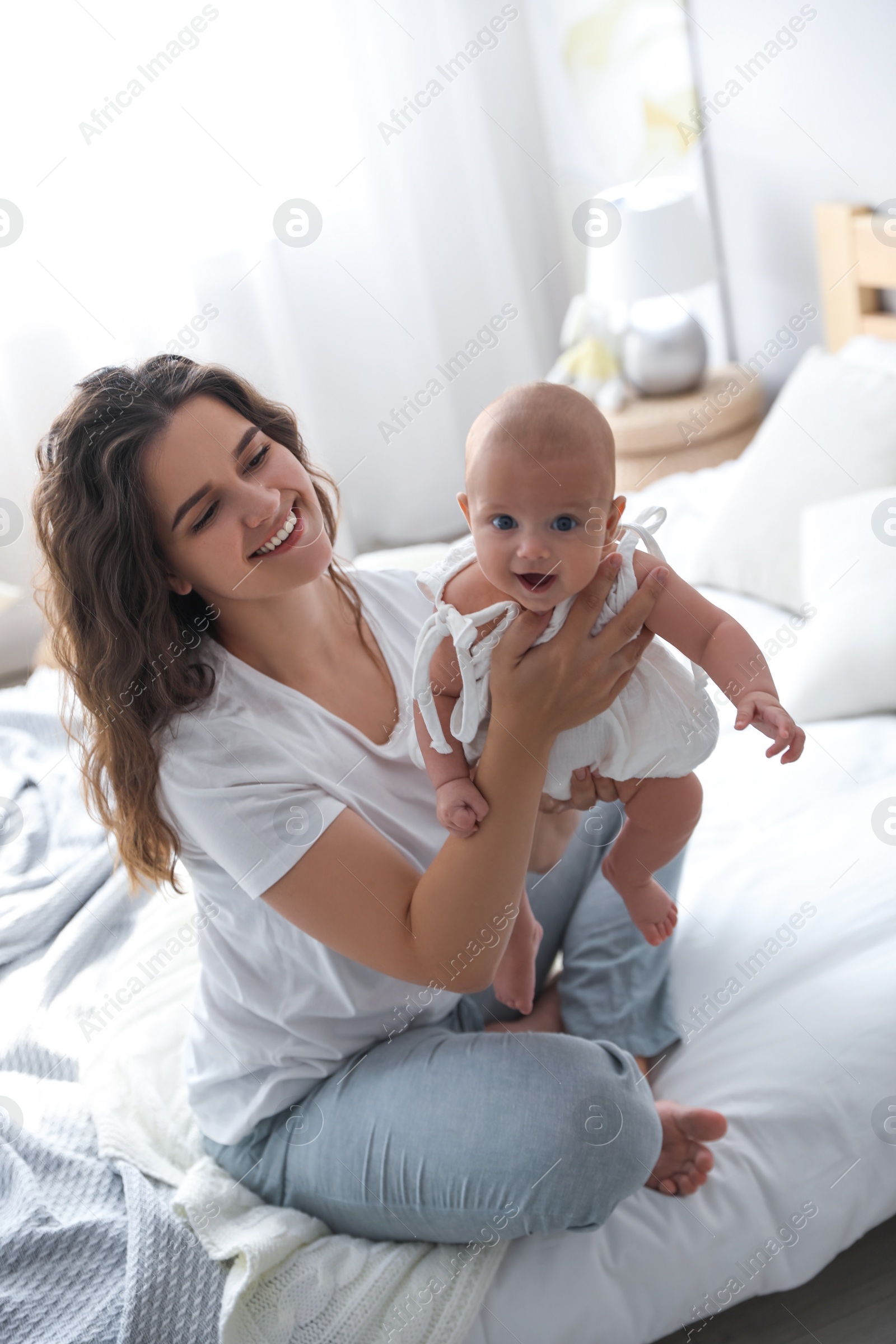 Happy young mother with her cute baby on bed at home Photo of Happy young mother with her cute baby on bed at home