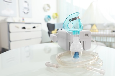 Modern nebulizer with face mask on white table in children's room. Equipment for inhalation Photo of Modern nebulizer with face mask on white table in children's room. Equipment for inhalation