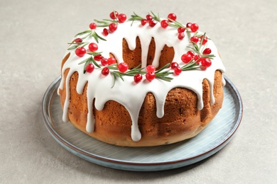 Traditional Christmas cake decorated with glaze, pomegranate seeds, cranberries and rosemary on light grey table Photo of Traditional Christmas cake decorated with glaze, pomegranate seeds, cranberries and rosemary on light grey table