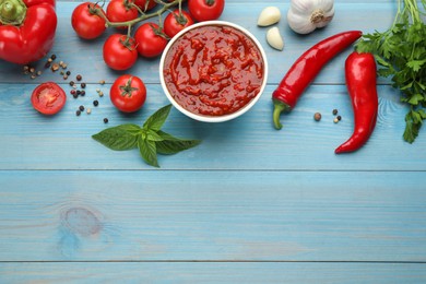 Delicious adjika sauce in bowl and ingredients on light blue wooden table, flat lay. Space for text Photo of Delicious adjika sauce in bowl and ingredients on light blue wooden table, flat lay. Space for text