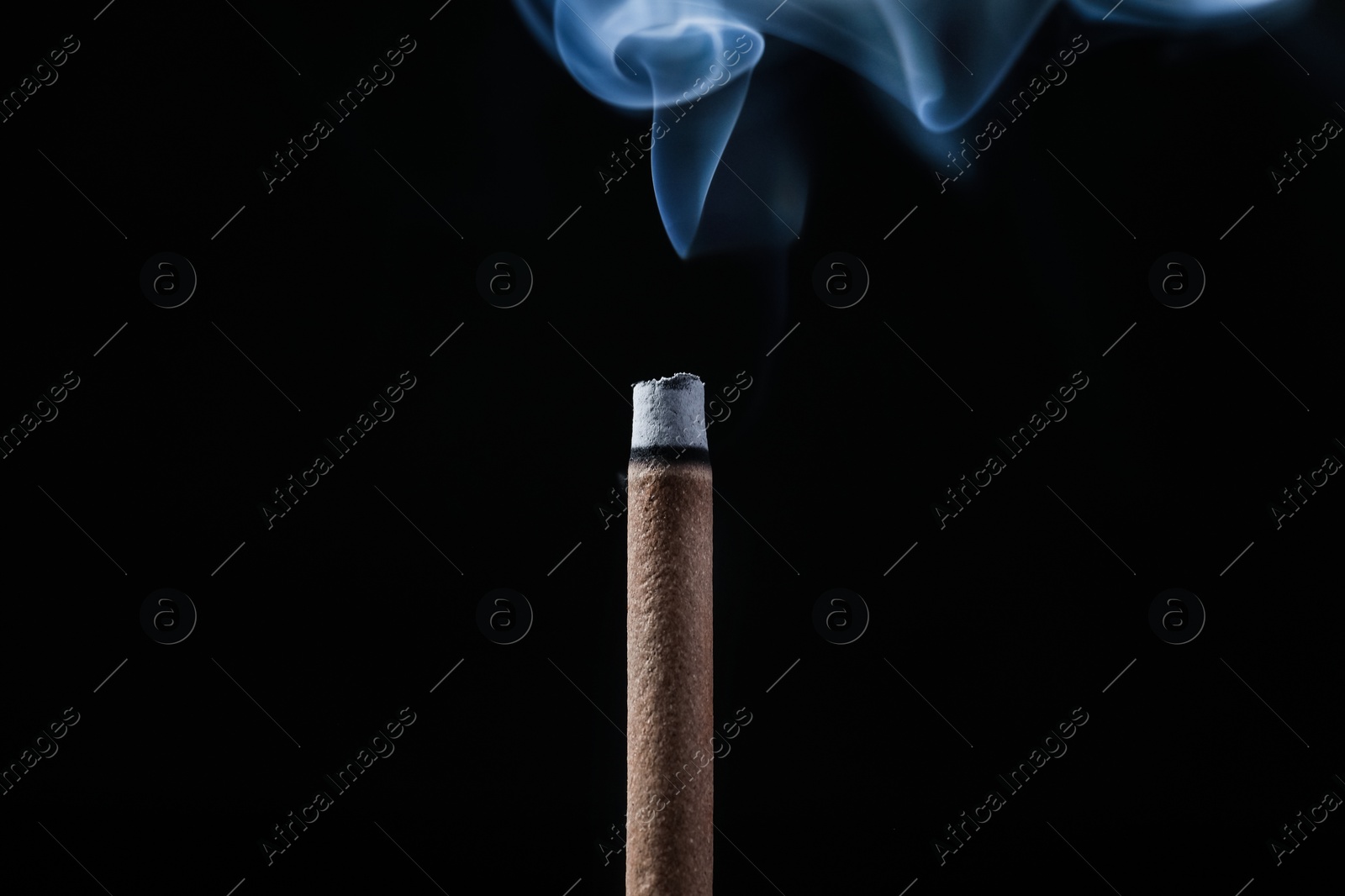 Incense stick smoldering on black background, closeup Photo of Incense stick smoldering on black background, closeup