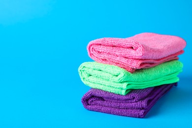 Stack of colorful microfiber cloths on light blue background. Space for text Photo of Stack of colorful microfiber cloths on light blue background. Space for text