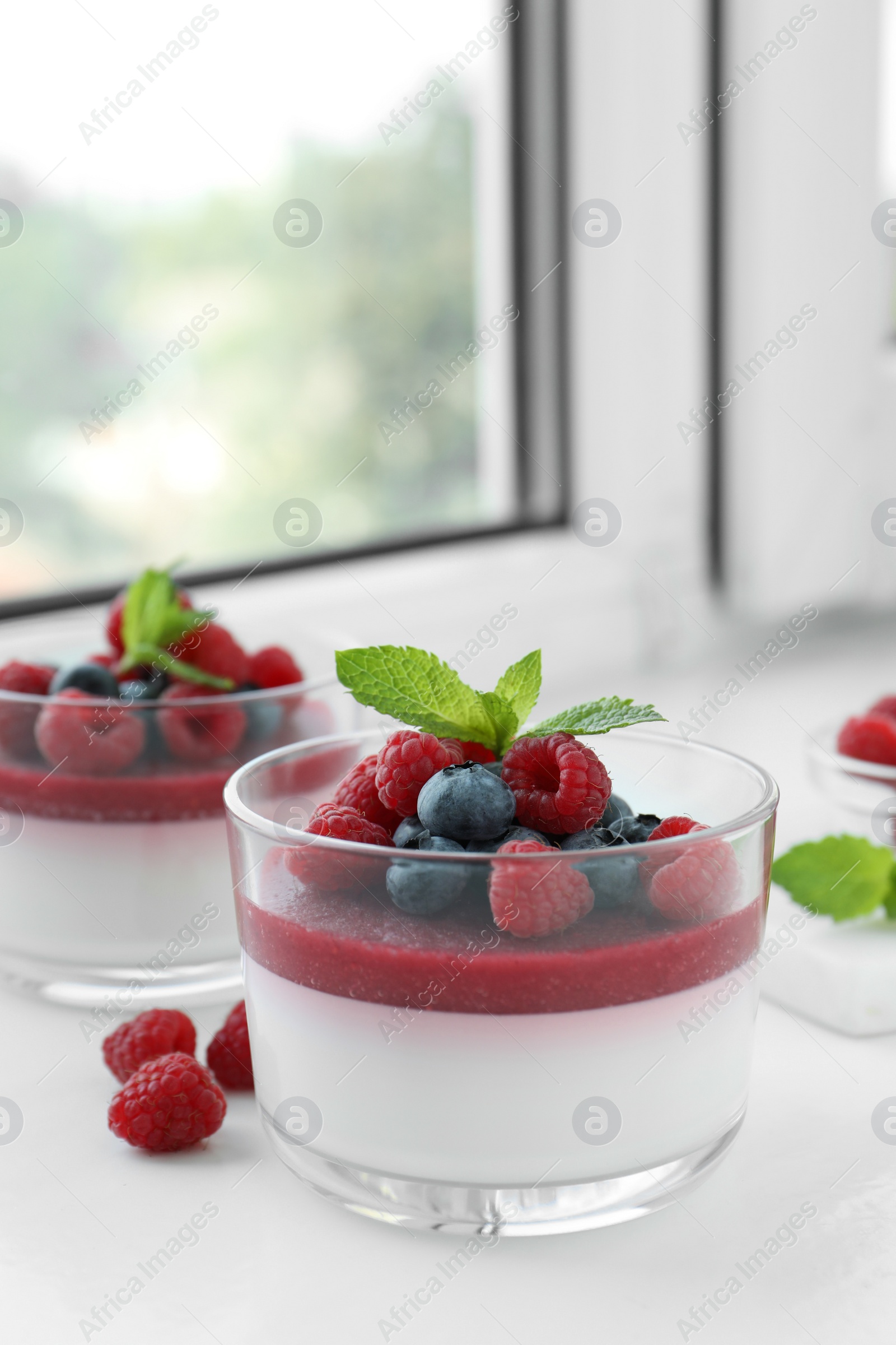 Delicious panna cotta with berries on window sill Photo of Delicious panna cotta with berries on window sill