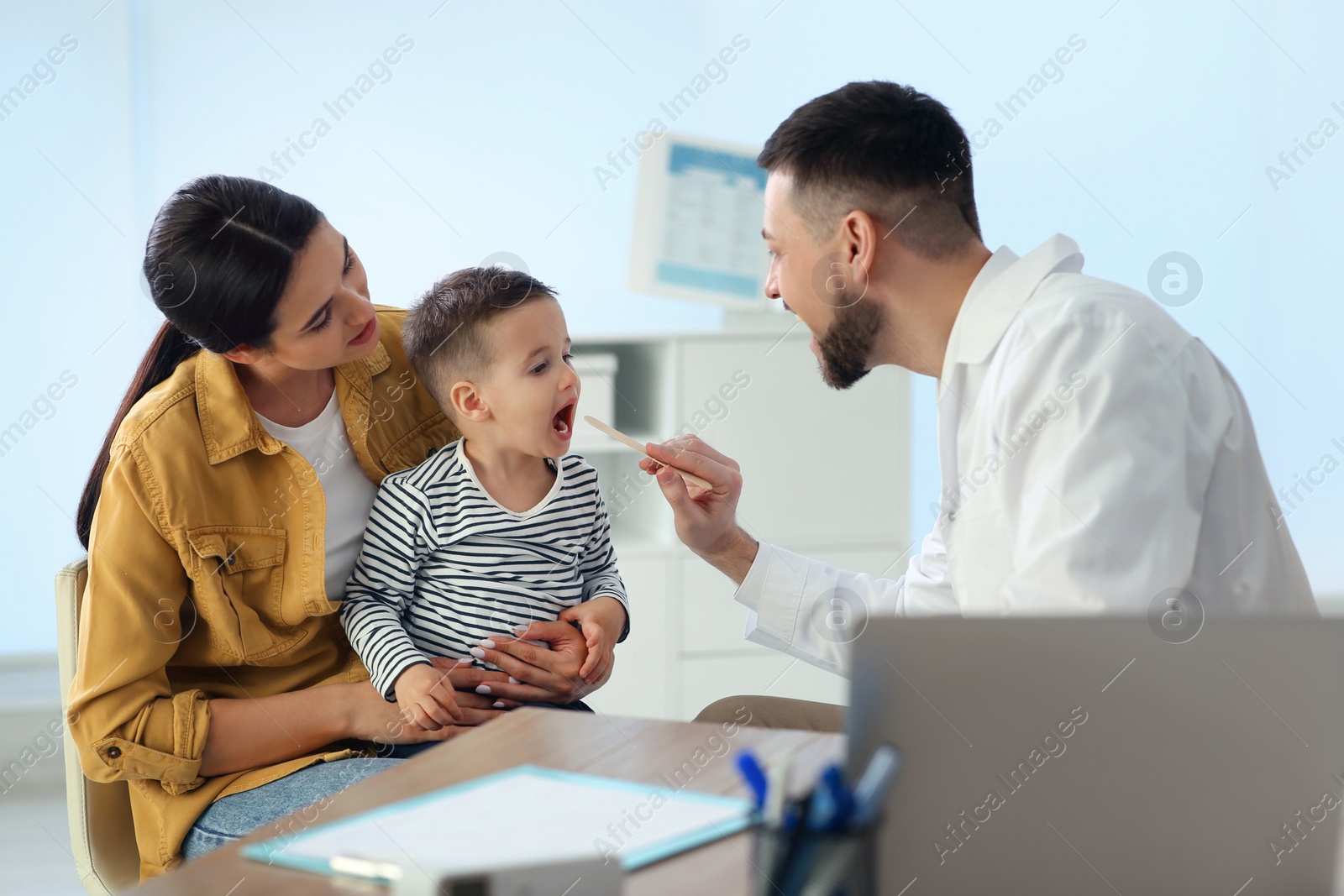 Mother and son visiting pediatrician in hospital. Doctor examining little boy Photo of Mother and son visiting pediatrician in hospital. Doctor examining little boy