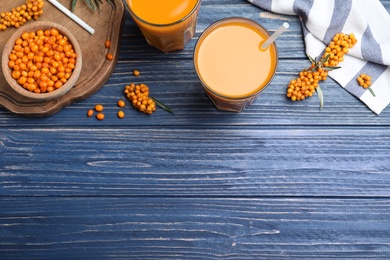 Flat lay composition with sea buckthorn juice on blue wooden table, space for text Photo of Flat lay composition with sea buckthorn juice on blue wooden table, space for text