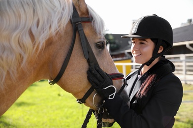 Young woman in horse riding suit and her beautiful pet outdoors on sunny day Photo of Young woman in horse riding suit and her beautiful pet outdoors on sunny day