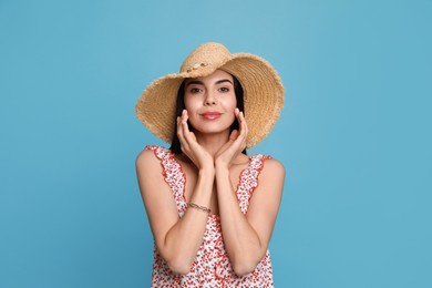 Photo of Beautiful young woman with straw hat on light blue background