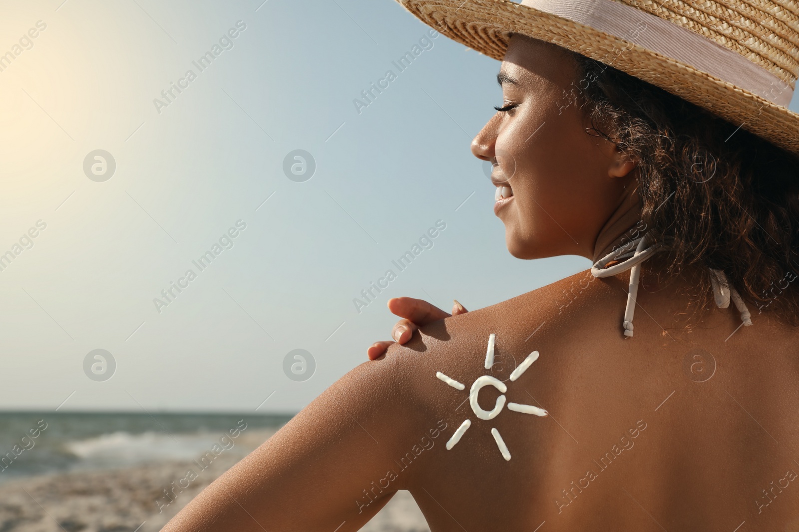 Beautiful African American woman with sun protection cream on shoulder at beach Photo of Beautiful African American woman with sun protection cream on shoulder at beach