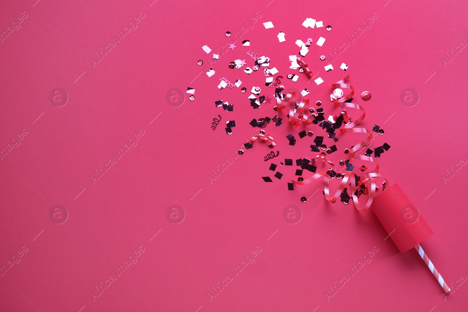 Shiny confetti and streamers with party cracker on pink background, top view. Space for text Photo of Shiny confetti and streamers with party cracker on pink background, top view. Space for text