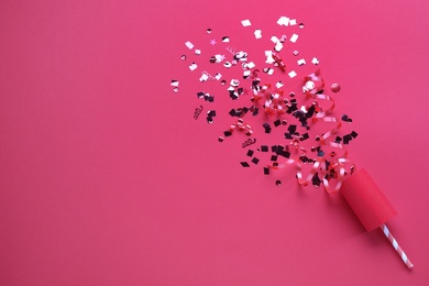 Shiny confetti and streamers with party cracker on pink background, top view. Space for text Photo of Shiny confetti and streamers with party cracker on pink background, top view. Space for text